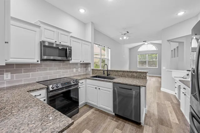 a kitchen with granite countertop a sink stainless steel appliances and window