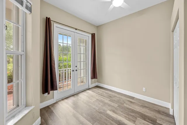 an empty room with wooden floor closet and windows
