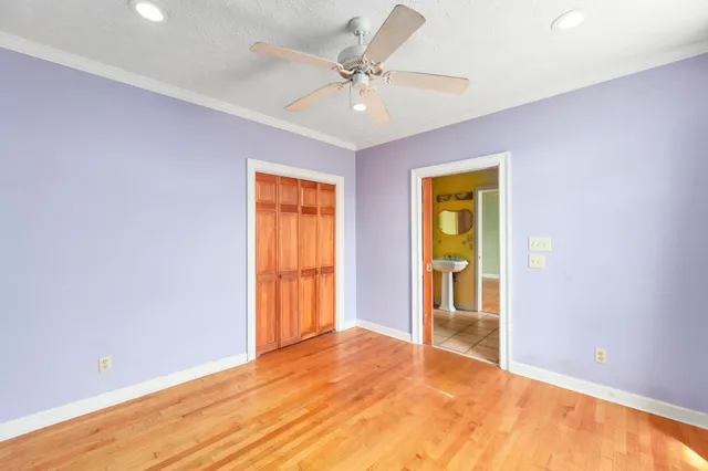 a view of an empty room with kitchen and a window