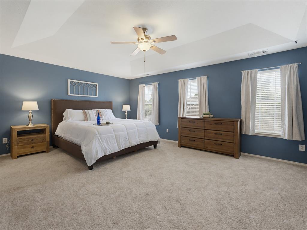 13268 Fencerow Road Fort Worth, TX 76244 - Photo 9 of 25 Spacious sleeping quarters featuring a tray ceiling, ceiling fan with integrated lighting, two windows with blinds, and light-toned carpeting