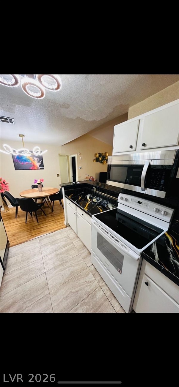 5131 South Lindell Road, Unit 205 Las Vegas, NV 89118 - Photo 8 of 22 Kitchen with white range with electric stovetop, visible vents, white cabinets, stainless steel microwave, and a textured ceiling