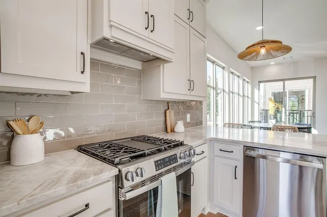 a kitchen with stainless steel appliances granite countertop a stove a sink and a white cabinets