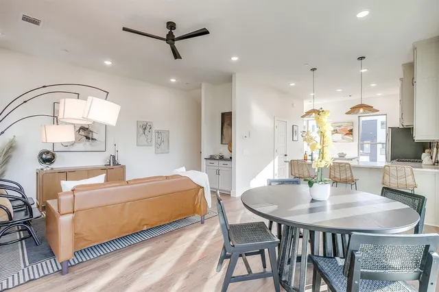 a living room with stainless steel appliances furniture a dining table and a chandelier