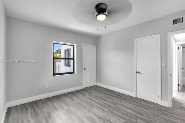 an empty room with wooden floor and windows