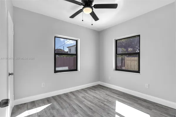 a view of an empty room with window and wooden floor