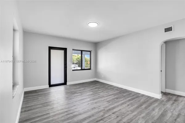 a view of an empty room with window and wooden floor