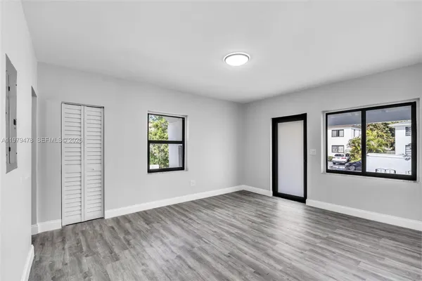 an empty room with wooden floor and windows