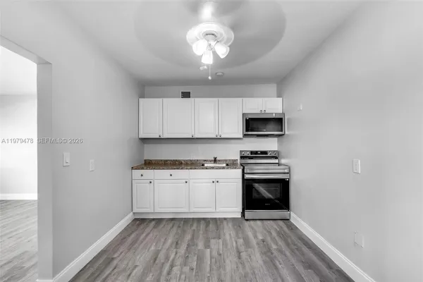 a kitchen with granite countertop stainless steel appliances a stove microwave and cabinets