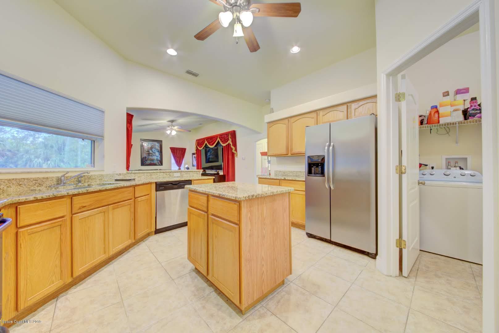 377 Tatum Road Southwest Palm Bay, FL 32908 - Photo 14 of 44 a kitchen with refrigerator cabinets and large window