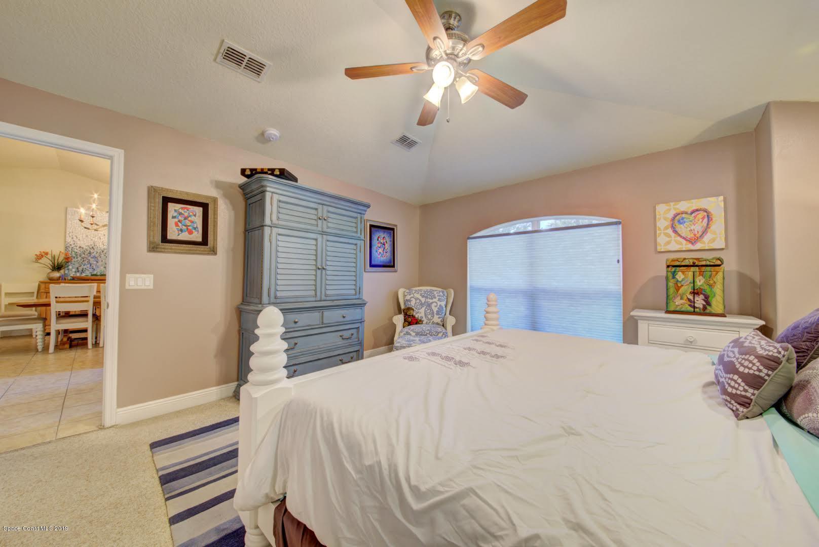 377 Tatum Road Southwest Palm Bay, FL 32908 - Photo 22 of 44 a spacious bedroom with a bed and a chandelier