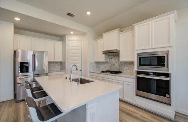 a kitchen with stainless steel appliances a stove a sink a microwave and cabinets
