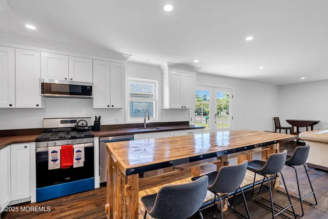 a kitchen with stainless steel appliances granite countertop a stove a sink a microwave a dining table and chairs with wooden floor