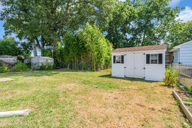 a backyard of a house with plants and large tree