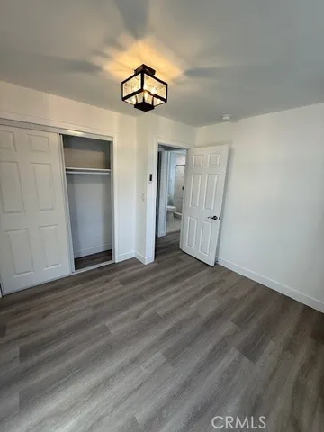 an empty room with wooden floor chandelier and windows