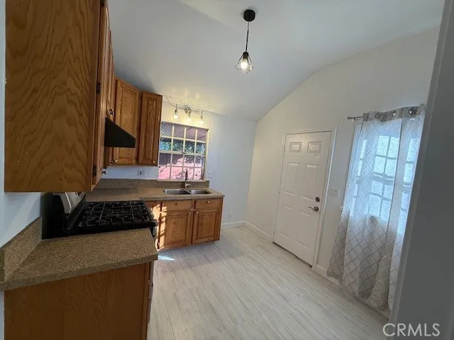 a kitchen with granite countertop a refrigerator a sink dishwasher a stove and a dining table with wooden floor