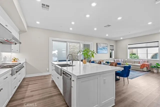 a large white kitchen with a stove a sink a refrigerator and a dining table with wooden floor