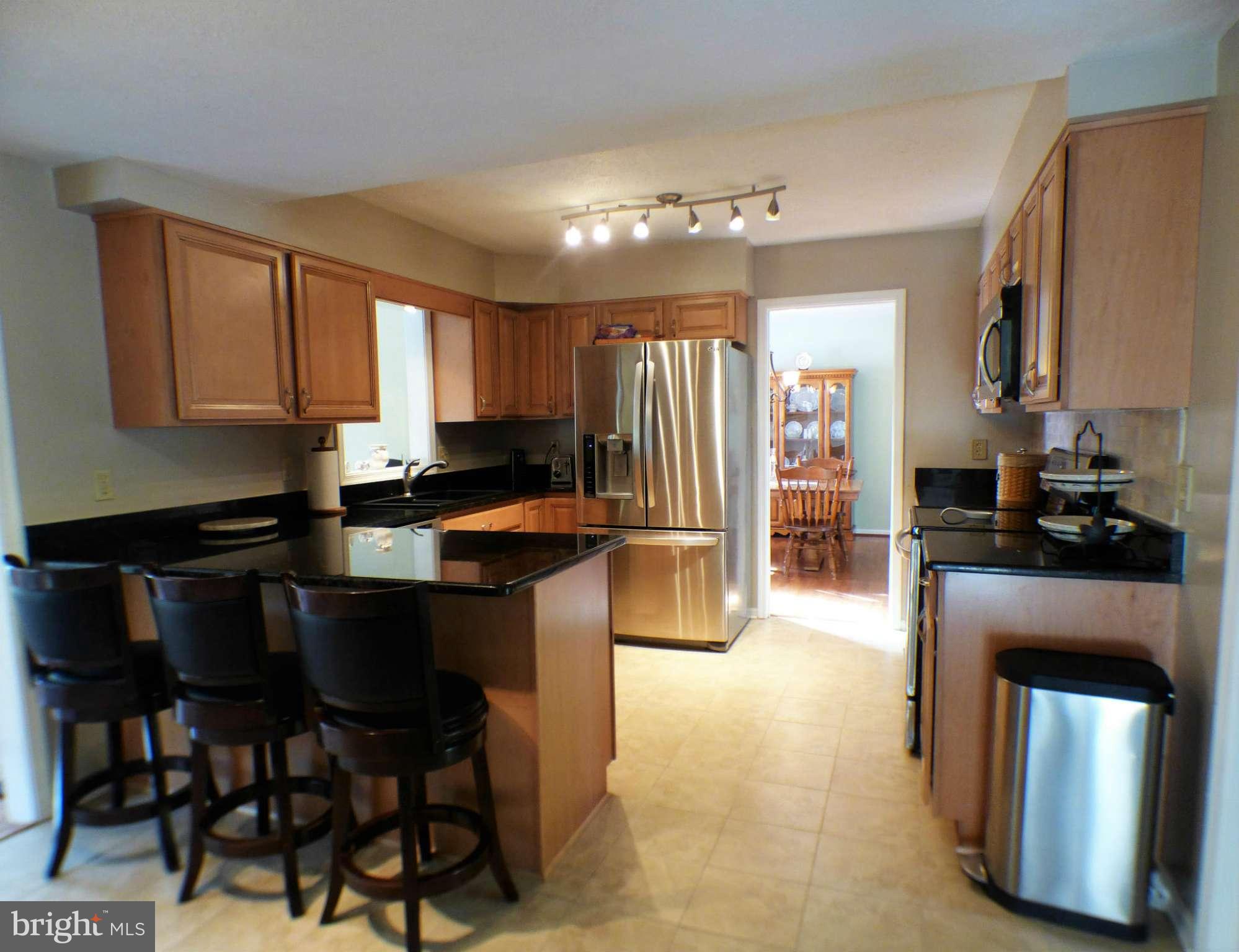 1521 Stinnett Road Huntingtown, MD 20639 - Photo 5 of 30 a kitchen with granite countertop a stove a refrigerator and chairs