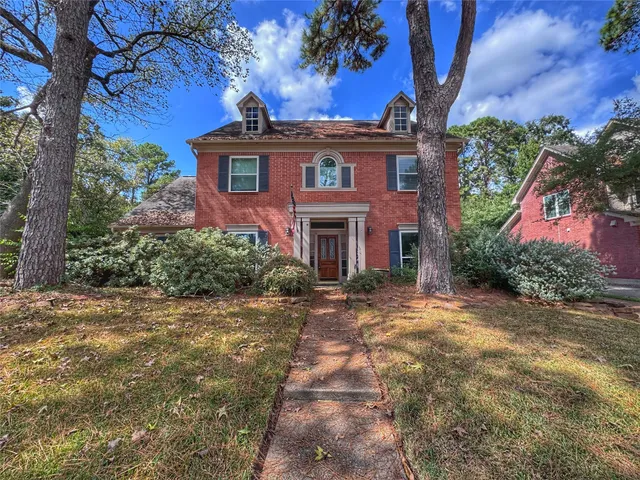 a view of a big house with a tree and plants
