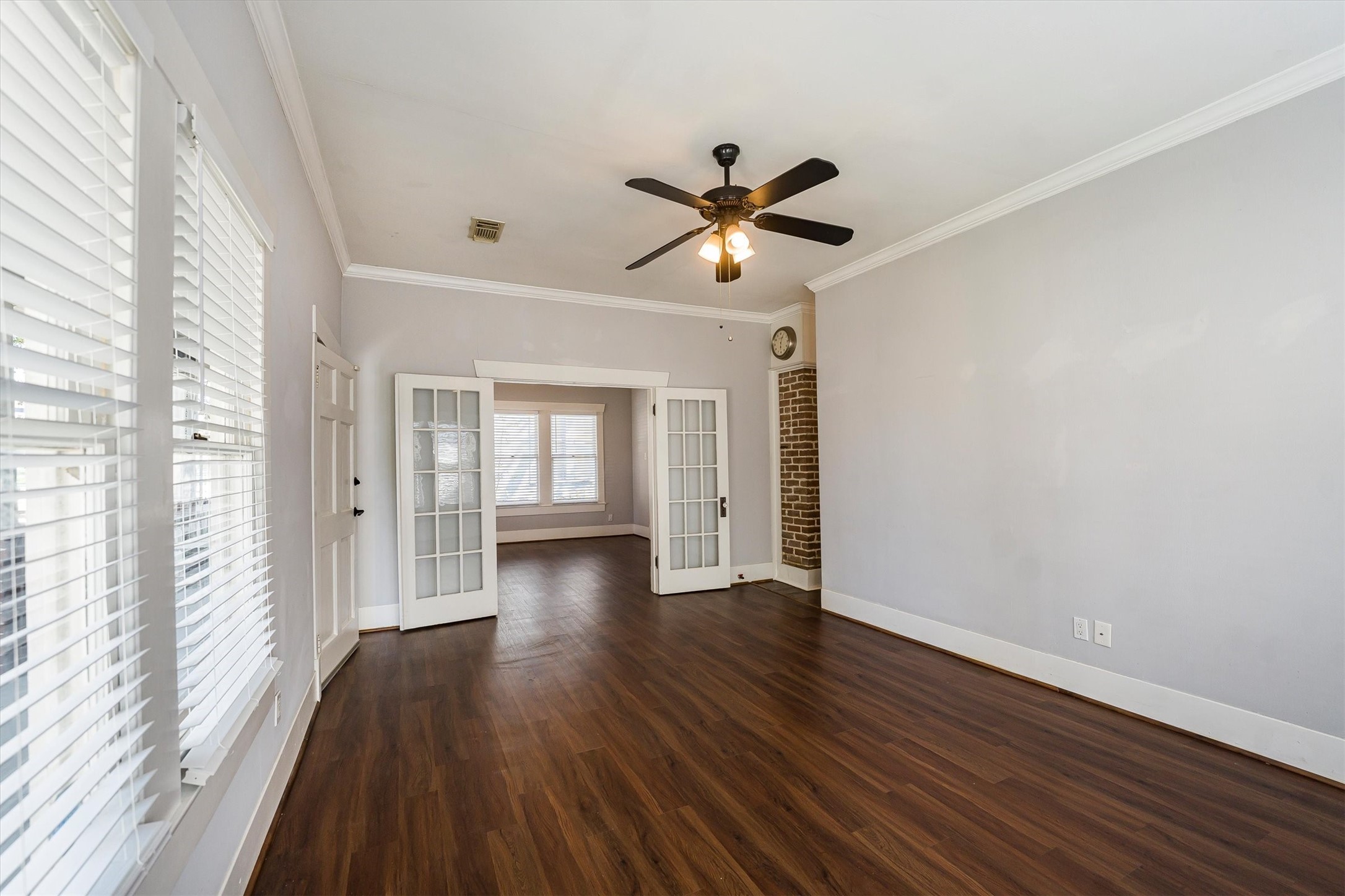 210 Tabor Street Houston, TX 77009 - Photo 4 of 18 This inviting living room features rich hardwood floors, a ceiling fan, and ample natural light through large windows. French doors lead to an adjacent space, adding charm and functionality.