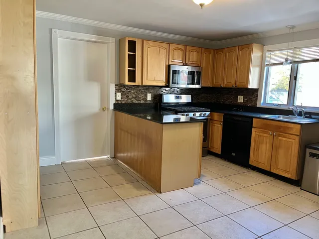 a kitchen with stainless steel appliances granite countertop a stove a sink and a microwave