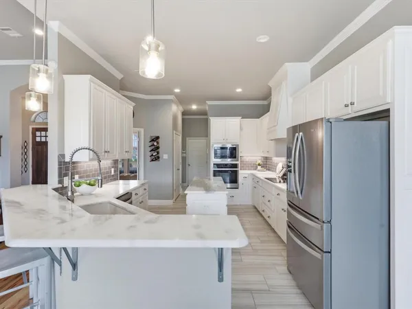 a kitchen with stainless steel appliances kitchen island granite countertop a refrigerator and a sink