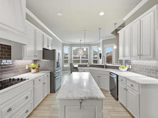 a large white kitchen with stainless steel appliances lots of counter space sink and cabinets