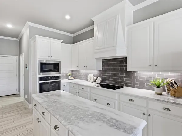 a kitchen with granite countertop white cabinets and stainless steel appliances