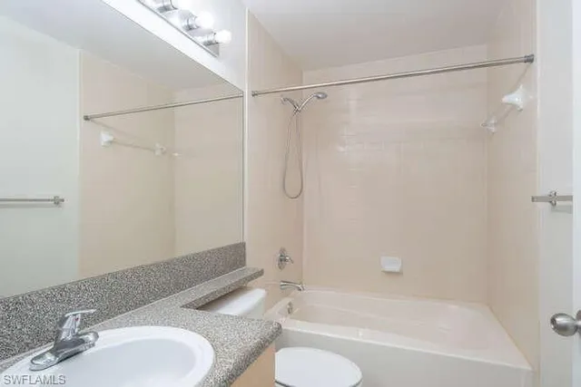 a bathroom with a granite countertop bathtub shower sink and toilet