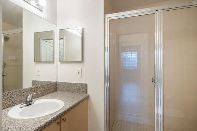 1220 Reserve Way, Unit 305 Naples, FL 34105 - Photo 15 of 20 a bathroom with a granite countertop sink and a mirror