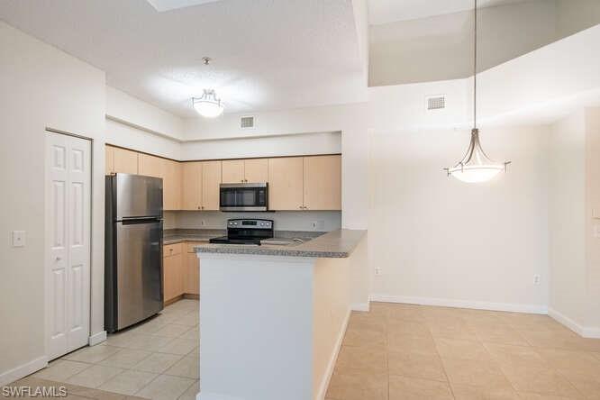 1220 Reserve Way, Unit 305 Naples, FL 34105 - Photo 8 of 20 a kitchen with stainless steel appliances a refrigerator sink and microwave