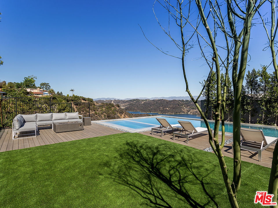 1632 Stradella Road Los Angeles, CA 90077 - Photo 13 of 41 a view of a backyard with lawn chairs under an umbrella