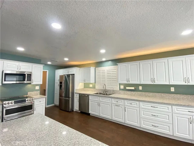 a large kitchen with stainless steel appliances lots of white cabinets