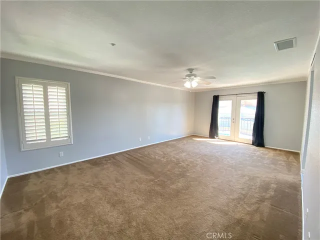 a view of an empty room with window and chandelier fan