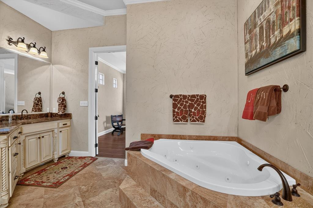 100 Canyon Ridge Trail Aledo, TX 76008 - Photo 25 of 38 Luxurious spa-inspired master bath featuring a corner soaking tub with integrated jets, dual-sink vanity with ample storage, travertine-look tile flooring, and warm neutral finishes throughout