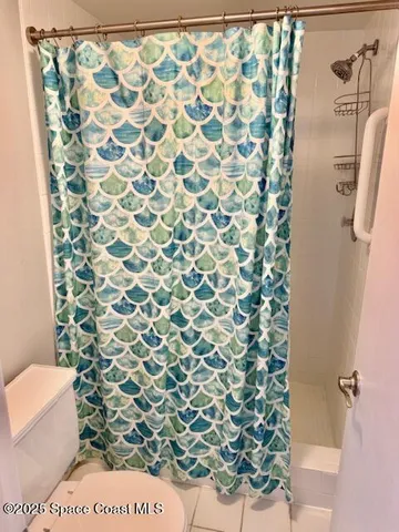 a bathroom with a toilet and a shower curtain