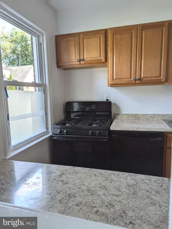 a kitchen with granite countertop a stove wooden floor and cabinets