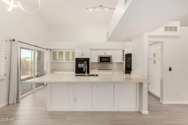 a large white kitchen with wooden floor and a sink