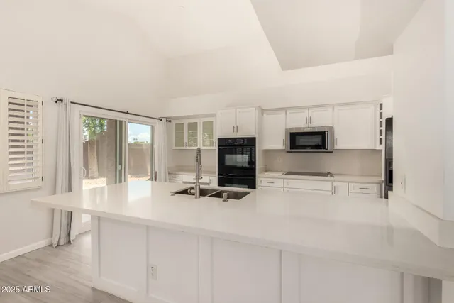 a kitchen with stainless steel appliances a stove a sink and white cabinets