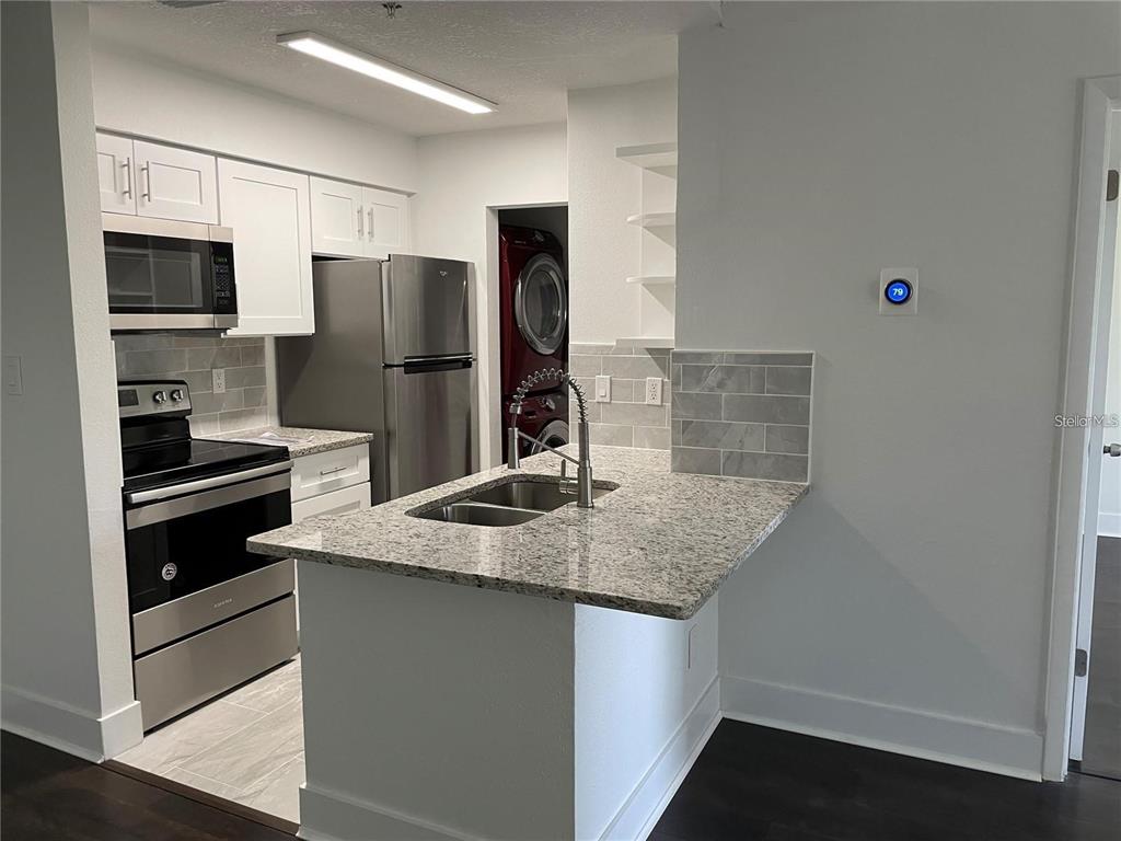 199 Afton Square, Unit 309 Altamonte Springs, FL 32714 - Photo 9 of 17 a kitchen with stainless steel appliances granite countertop a sink stove and refrigerator
