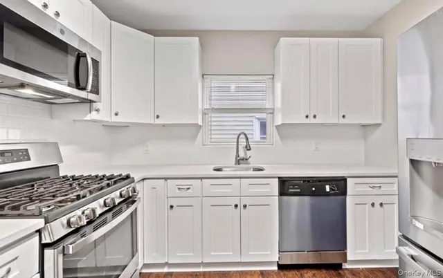 a kitchen with white cabinets and appliances