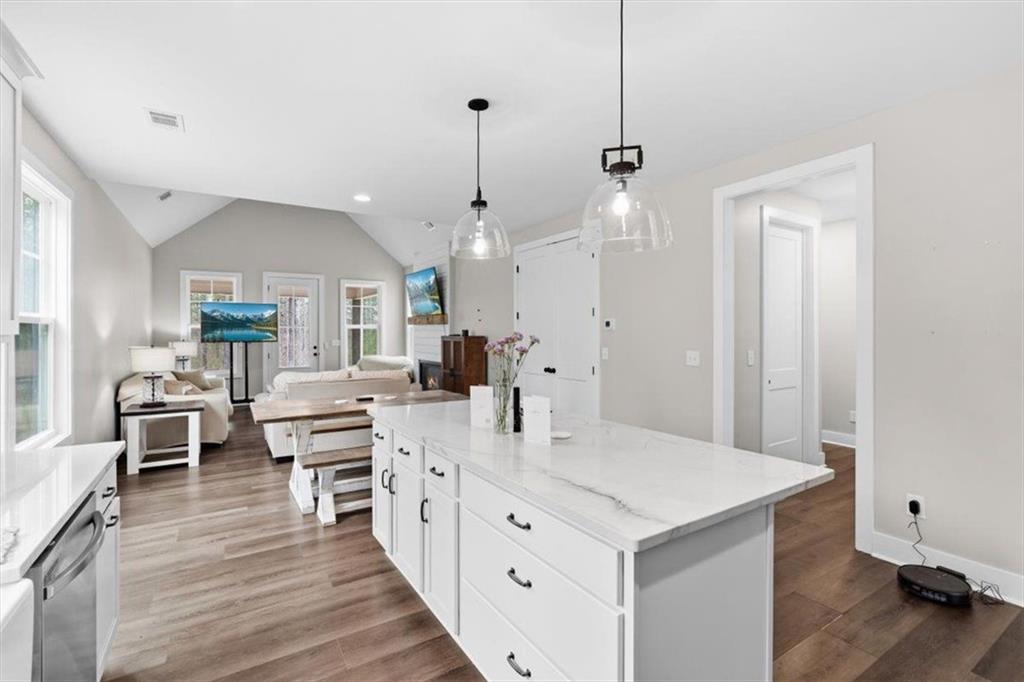 1270 McGarity Road Temple, GA 30179 - Photo 20 of 58 a large white kitchen with a large island a sink dishwasher and a dining table with wooden floor