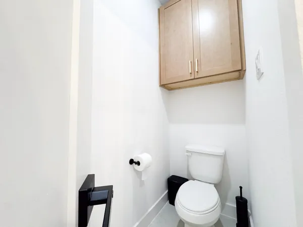 a white toilet sitting next to a white cabinet