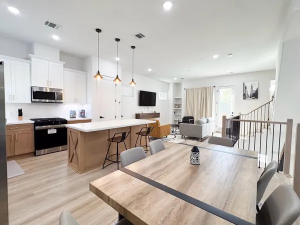 an open kitchen with wooden floor and stainless steel appliances