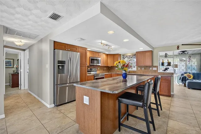 a kitchen with stainless steel appliances granite countertop a table chairs and a refrigerator