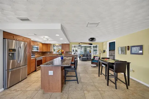 a living room with stainless steel appliances furniture a rug and a kitchen view