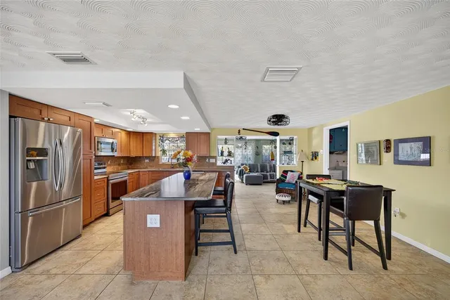a living room with stainless steel appliances furniture a rug and a kitchen view