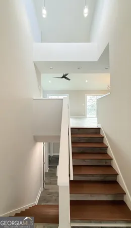 an empty room with wooden floor and a ceiling fan