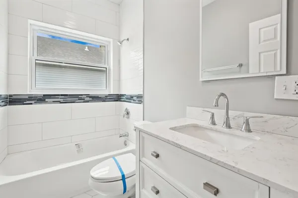 a bathroom with a granite countertop sink mirror vanity and toilet