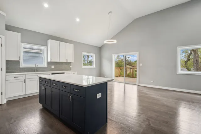 a kitchen with a stove a sink a wooden floor and white cabinets