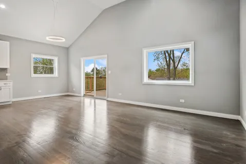 a view of an empty room with wooden floor and window